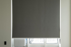 Roller blinds closeup on the window in the interior. Blackout roller shades for big windows. chain control. Grey color, texture material. Sun protection and window decoration.